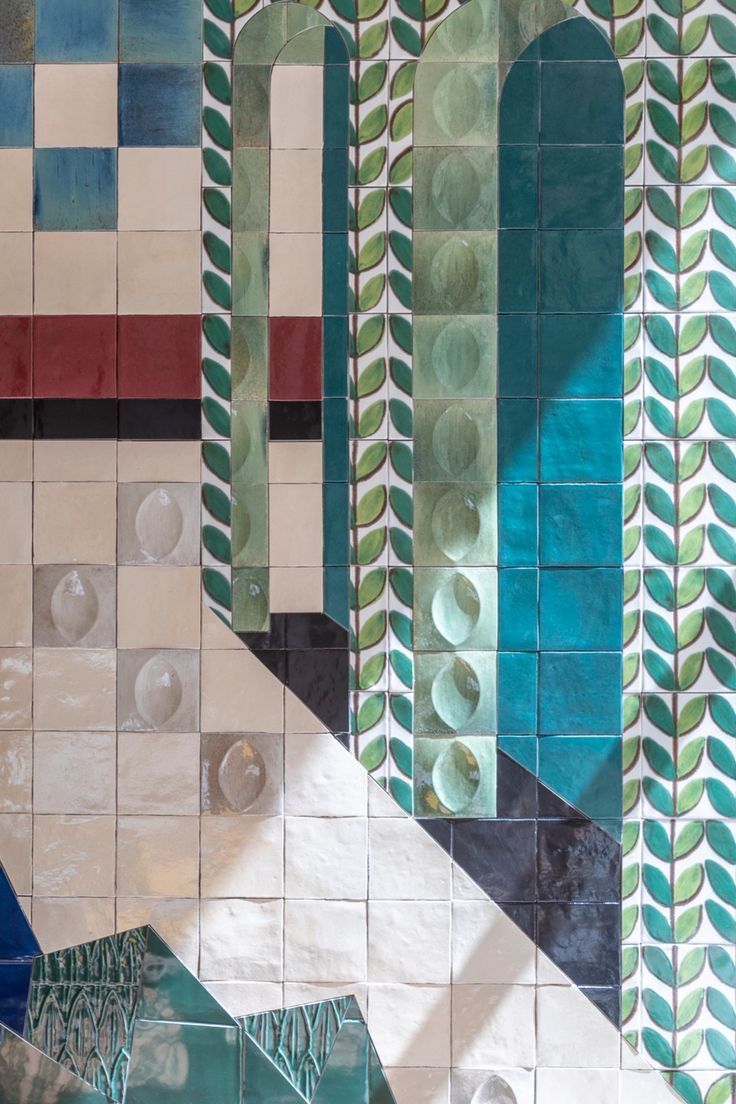 an artistic tile wall with green and blue designs