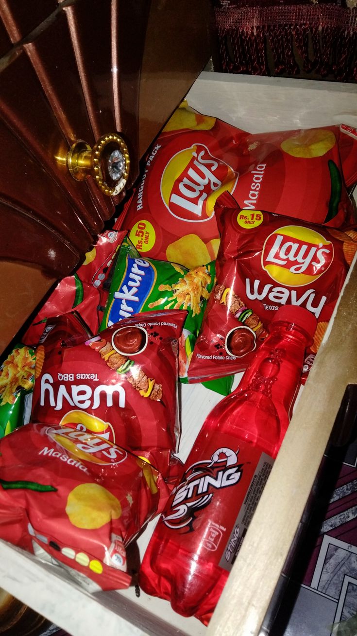 several bags of chips are sitting in a drawer on the floor next to a fan