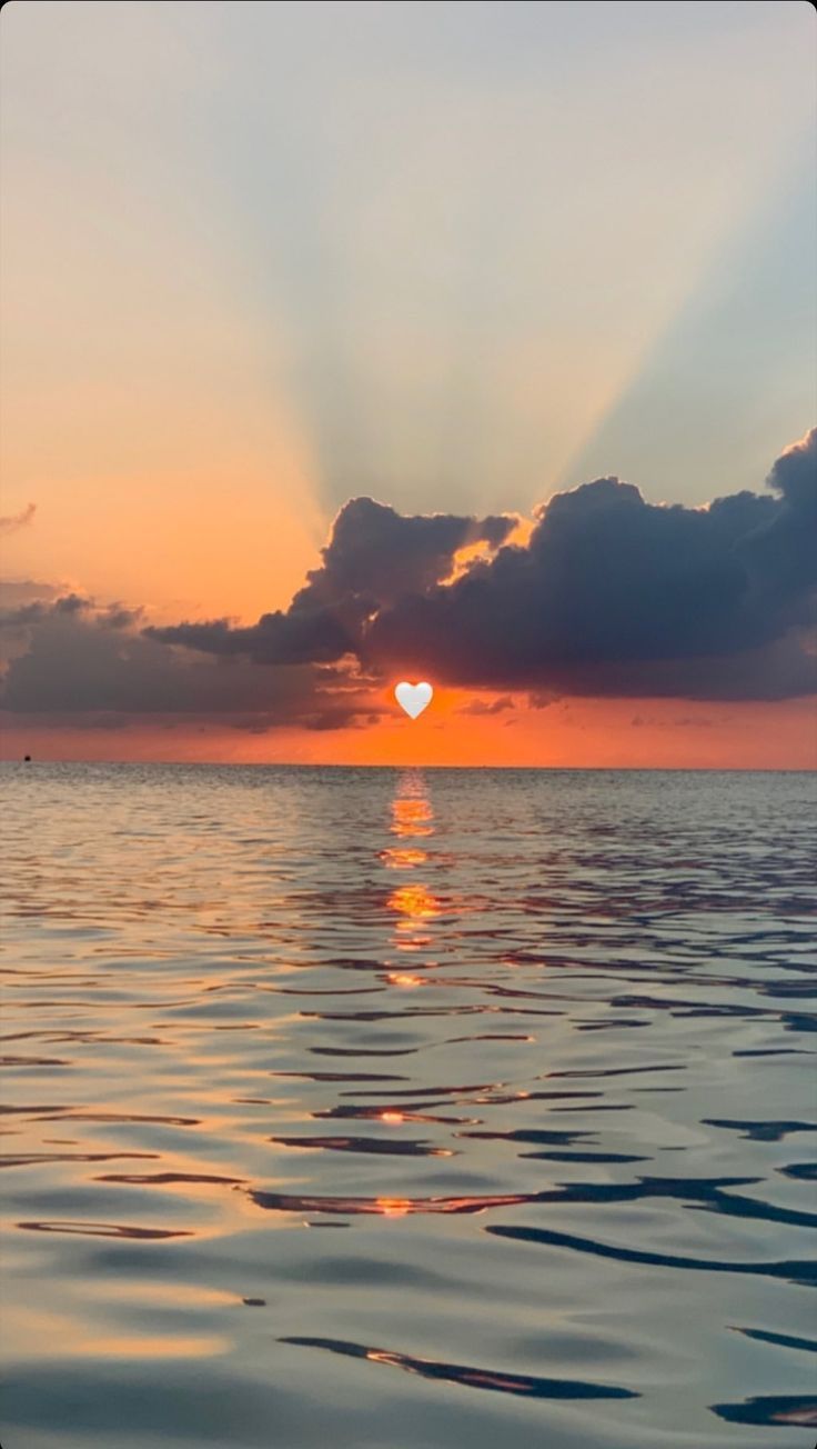 the sun is setting over the ocean with clouds in the sky and water below it