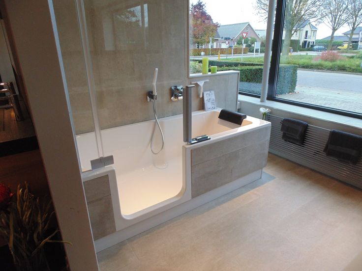 a bathroom with a walk in shower next to a large window and a bathtub