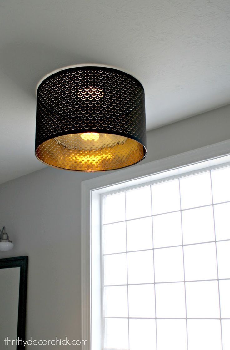 a light fixture hanging from the ceiling above a window in a room with white walls