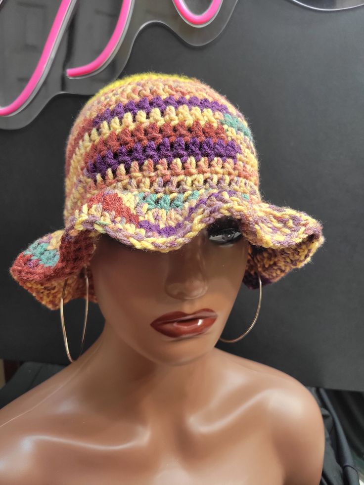 a mannequin head wearing a multicolored crocheted hat with large hoop earrings