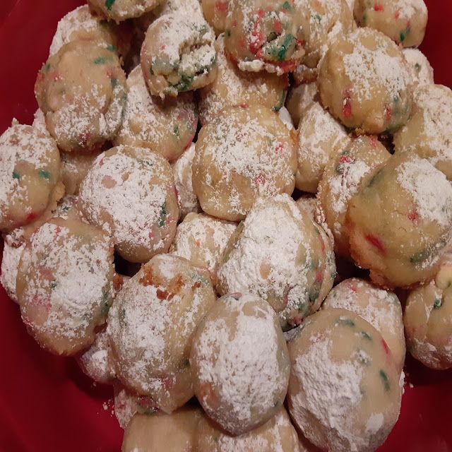 a red bowl filled with cookies covered in powdered sugar