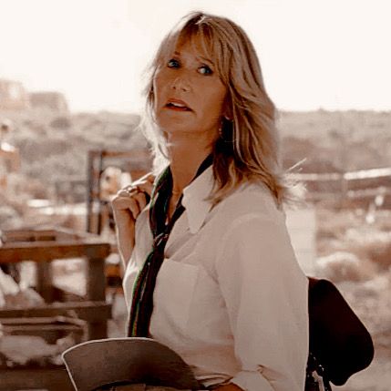 a woman in white shirt and black tie standing next to a building with buildings in the background