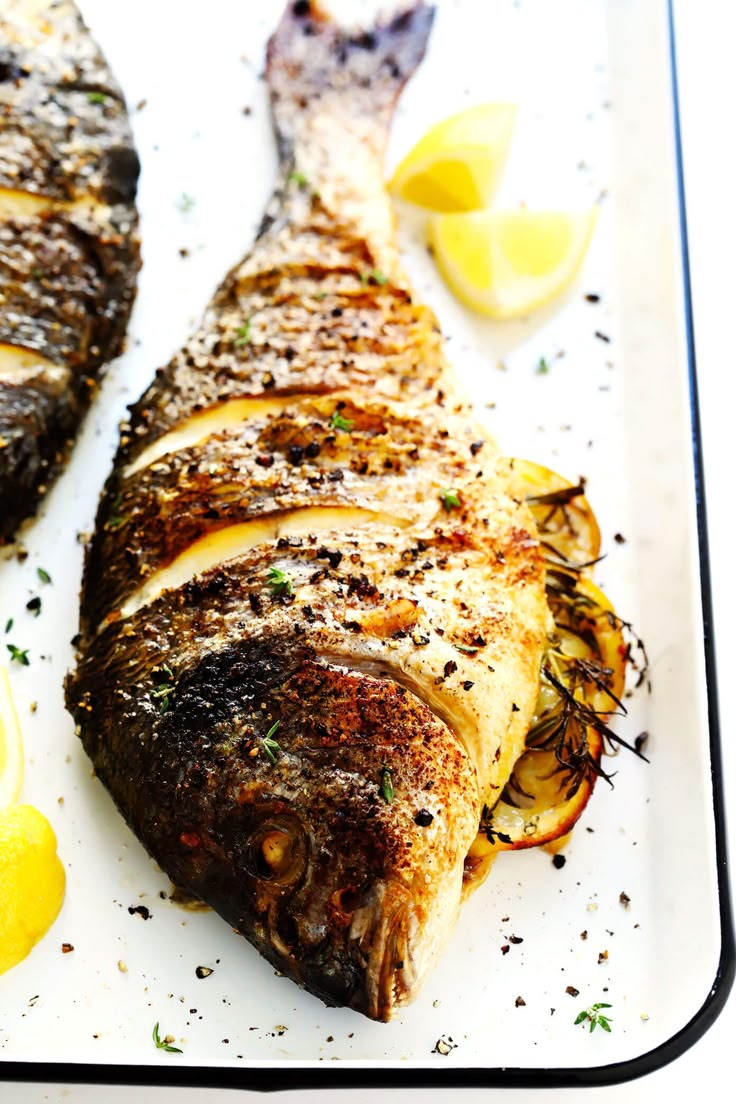 two pieces of fish on a plate with lemons