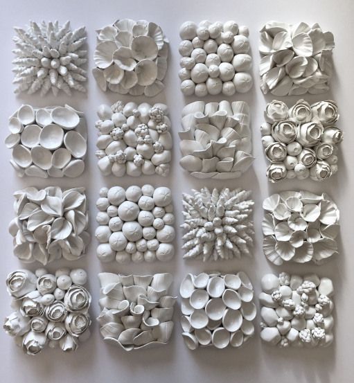 many white objects are arranged in rows on the wall, and one is made out of paper