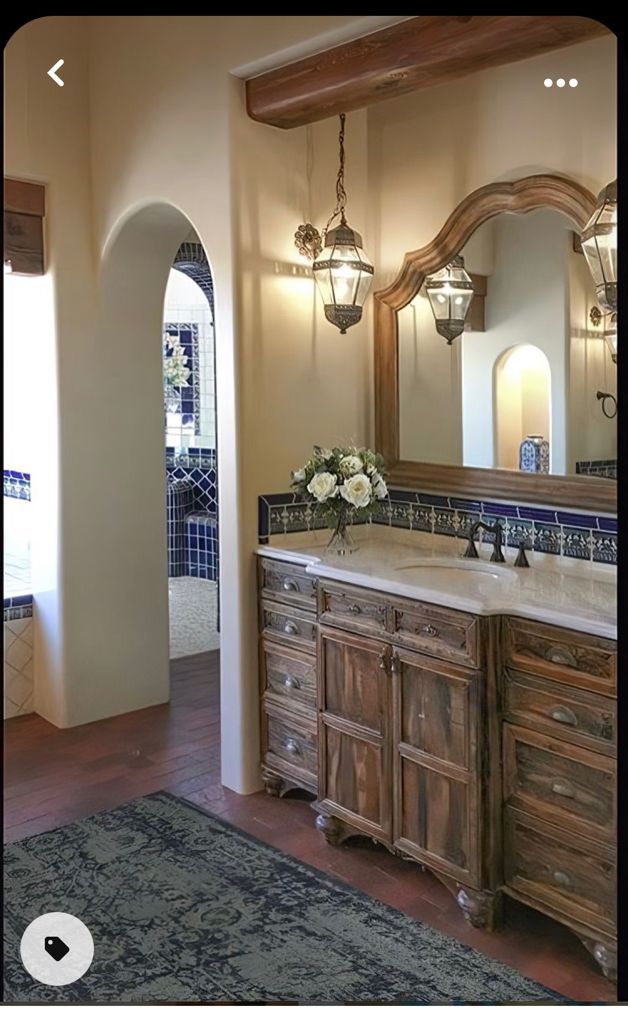 a bathroom with a double sink and wooden cabinet in the middle, along with an arched doorway leading to another room