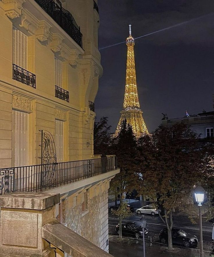 the eiffel tower lit up at night in paris, france as seen from an apartment balcony