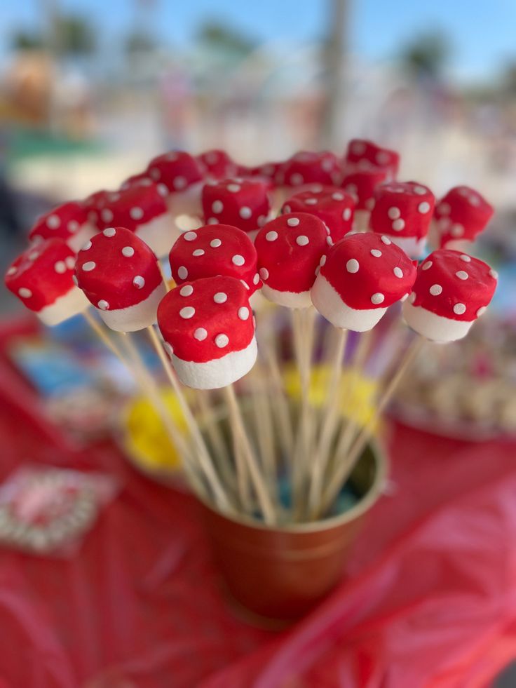 red and white cake pops with polka dots in a brown cup on a pink table cloth