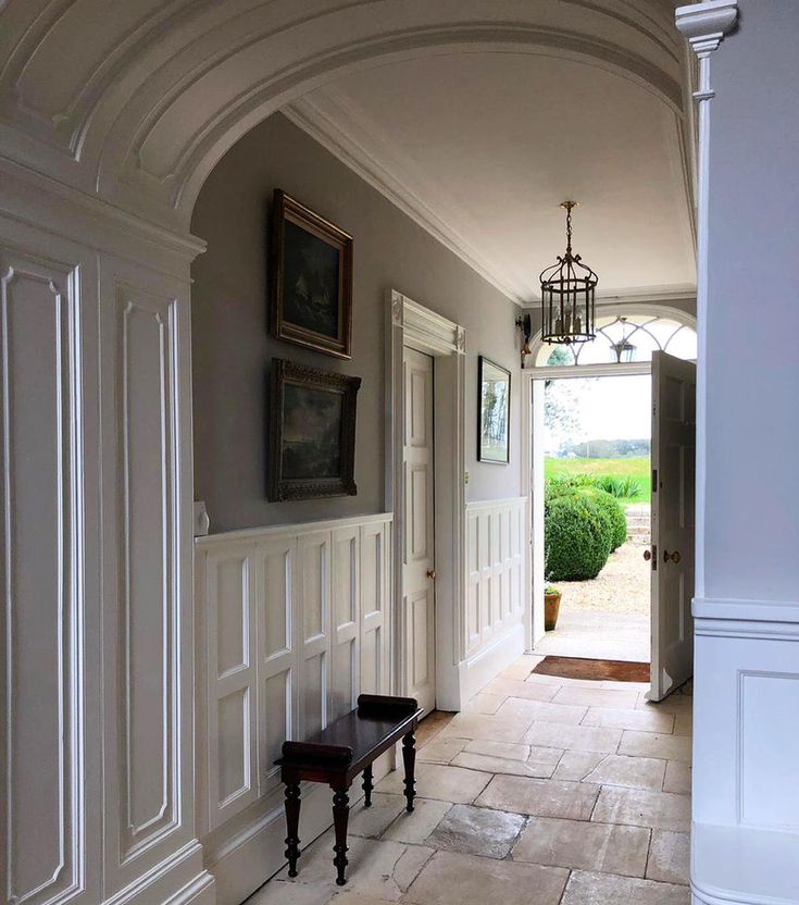 an archway leading into a hallway with two benches and pictures on the wall above it