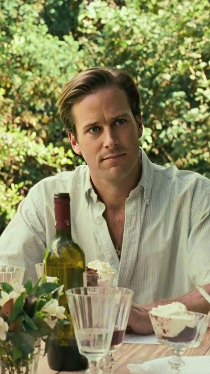 a man sitting at a table with wine and food