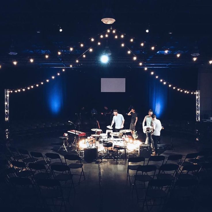 a group of people standing on top of a stage with chairs and lights around them