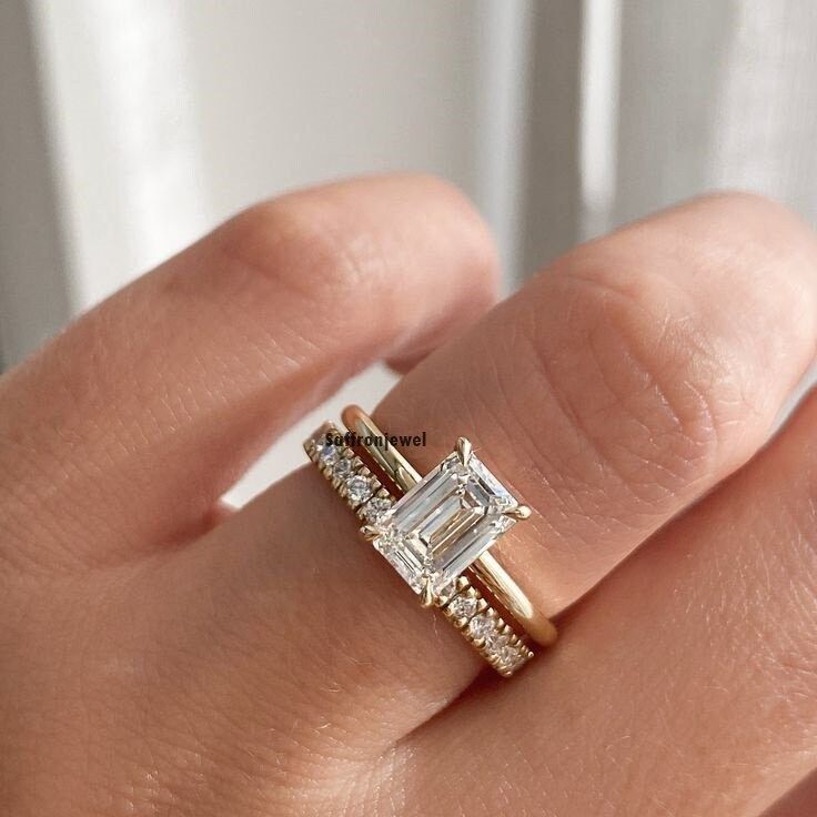 a woman's hand with a diamond ring on top of her finger and the engagement band