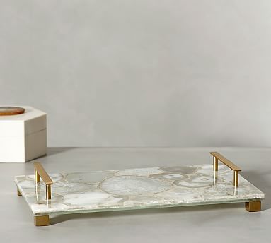 a white marble tray with gold handles on a grey surface next to a small box