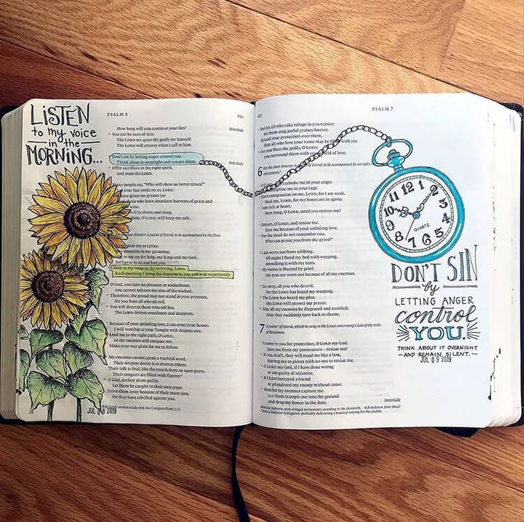 an open bible on a wooden table with a clock and sunflowers in it