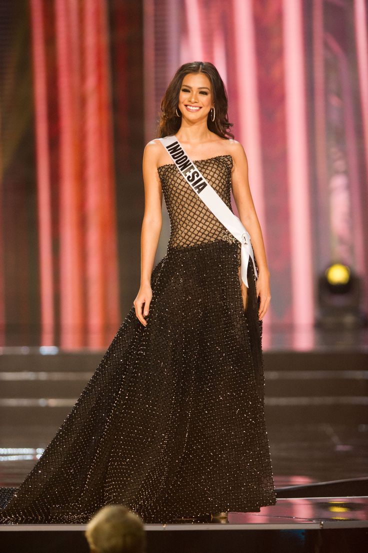 a woman in a black and white gown on stage with an award for the miss america pageant