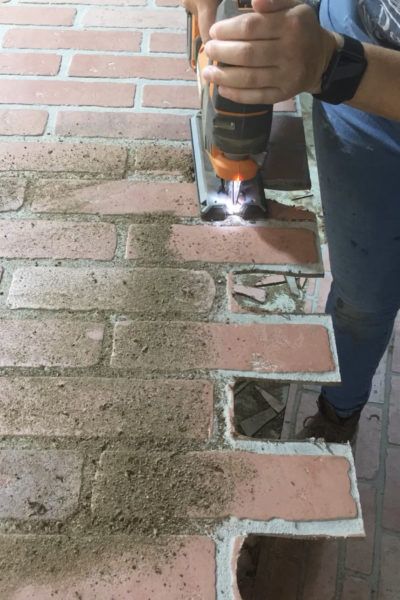 a man using a drill to fix a brick wall