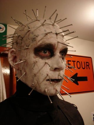 a man with spikes on his head is standing in front of a street sign