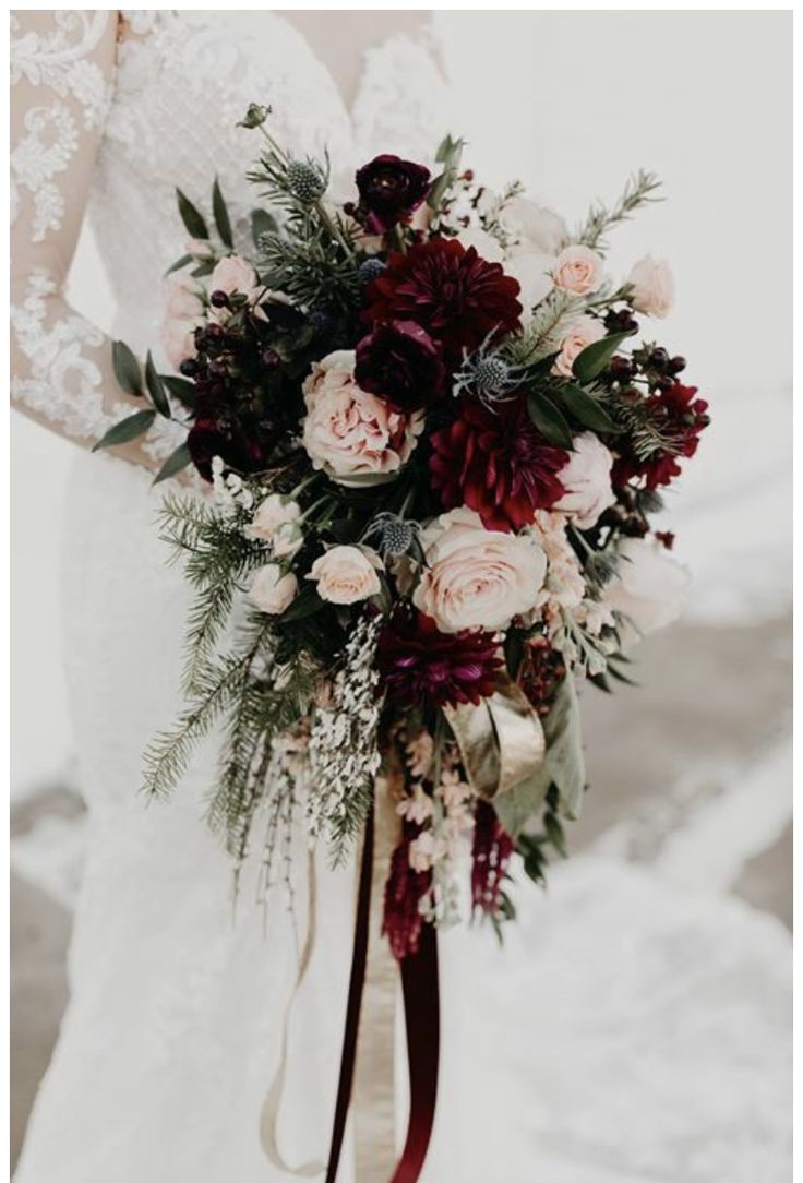 a bridal holding a bouquet of red and white flowers