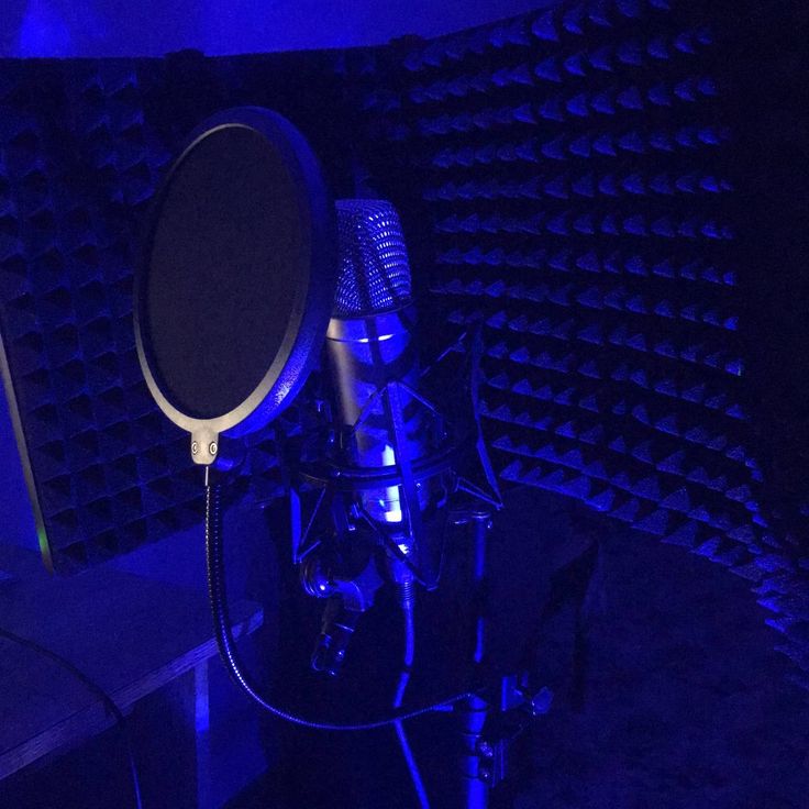 a microphone in a dark room with blue lights on the walls and black speakers behind it