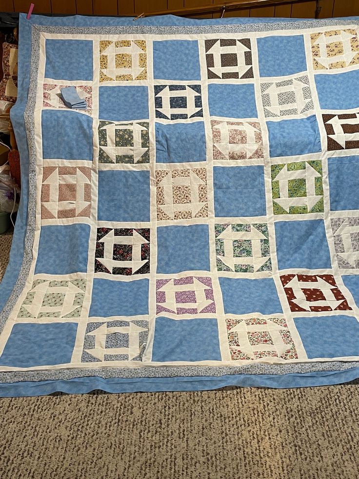 a blue and white quilt sitting on top of a bed