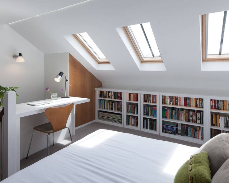 there is a bed in the room with bookshelves and a desk under it