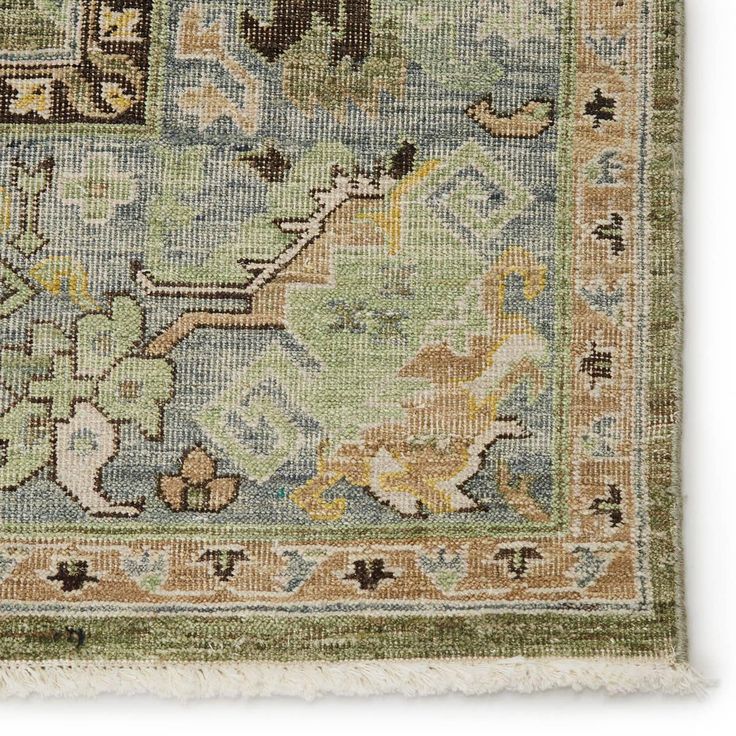 an antique rug with green, yellow and blue colors on the edges is displayed against a white background