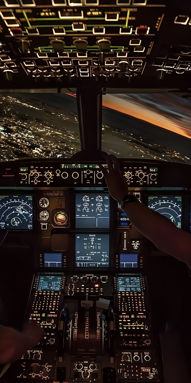 two pilots in the cockpit of an airplane at night with their hands on the controls