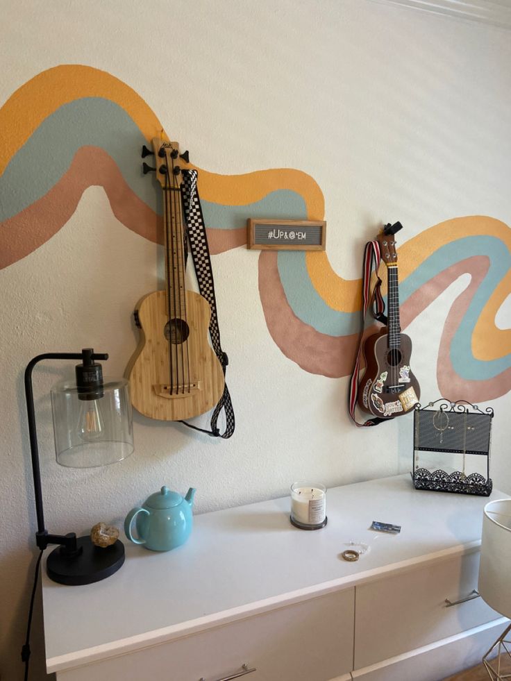 a white dresser topped with a guitar next to a wall mounted music instrument on it