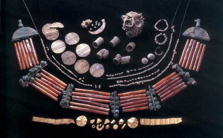 an assortment of ancient jewelry is displayed on a black surface with gold and silver accents