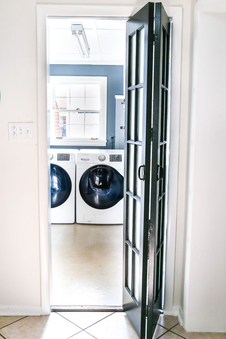 an open door leading to a washer and dryer in a room with tile flooring