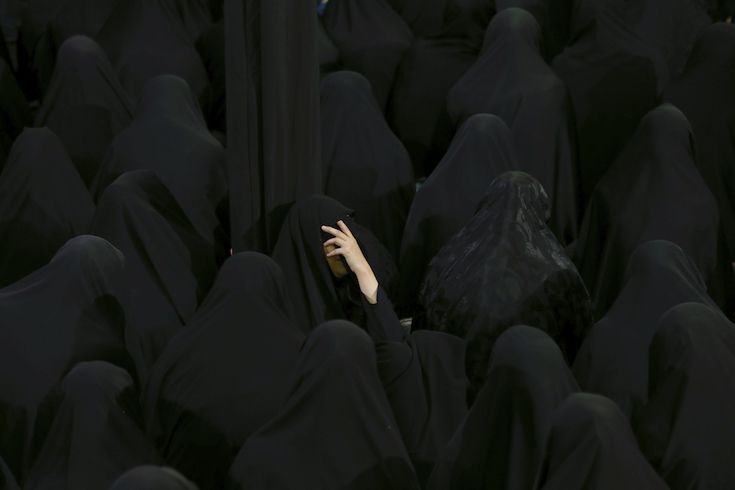 a group of people in black clothing with their hands on the back of one person's head