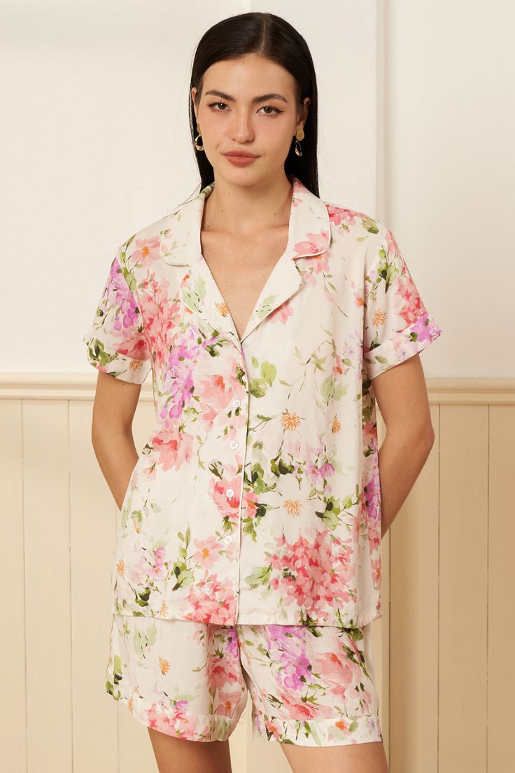 This exquisite pajama set showcases an exclusive romantic floral print on luxuriously soft, high-quality rayon. The set features a button-front top with a collar and comfortable elasticized shorts with a drawstring. Perfect for everyday lounging, nighttime comfort, or as elegant bridesmaid pajamas. FABRIC: 100% Rayon LENGTH: Top of shoulder to hem 36" STYLE: PJ-19154 in SOFT KISS IVORY -SOFKI-P99 *Model is wearing size small *Machine was on cold, and hang flat to dry. Feminine Floral Print Sleepwear For Vacation, Feminine Floral Print Sleepwear For Pajama Party, Floral Print Relaxed Top For Pajama Party, Spring Sleepwear With Camp Collar For Pajama Party, Camp Collar Sleepwear For Pajama Party In Spring, Feminine Floral Print Sleepwear For Summer, Feminine Floral Print Summer Sleepwear, Feminine Floral Print Pajama Party Sets, Floral Print Relaxed Fit Sets For Daywear