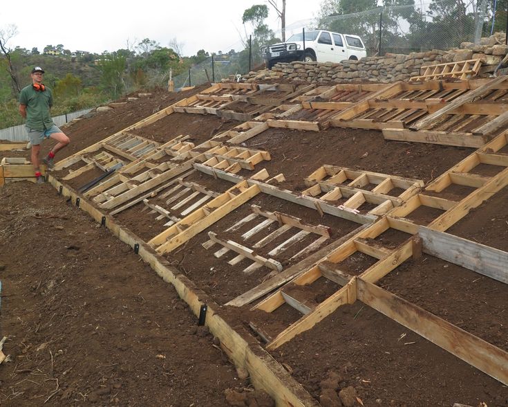 a man standing on top of a pile of wooden pallets next to a truck