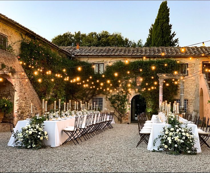 an outdoor dining area with tables, chairs and lights strung from the building's roof