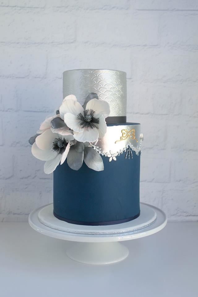 a blue and silver cake with flowers on top