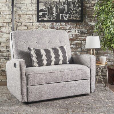 a gray couch sitting in front of a brick wall