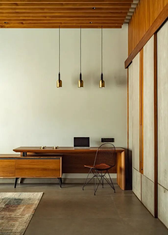 a room with a desk, chair and lamp hanging from the ceiling over it's windows