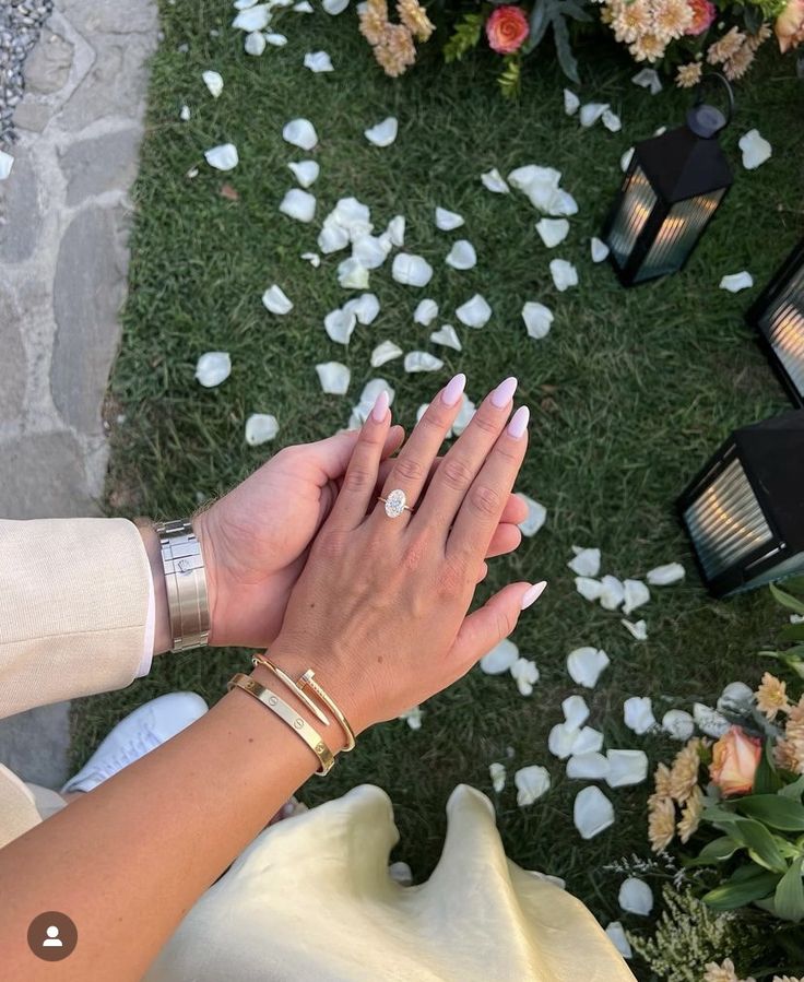 two people are holding hands in front of flowers and candles on the ground with petals scattered all around them