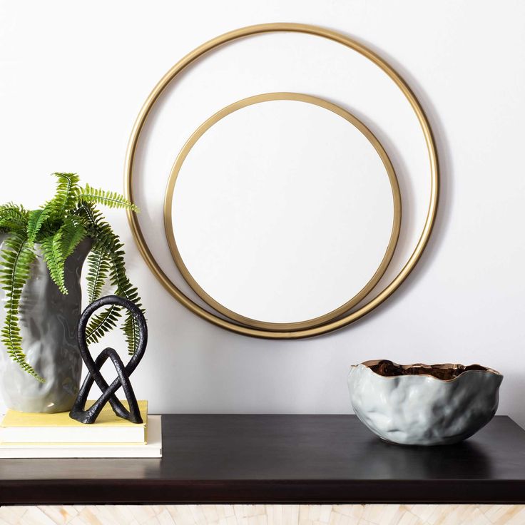 a table with a vase, plant and mirror on it