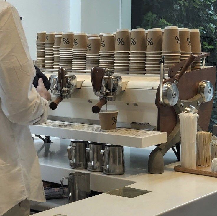 a coffee machine sitting on top of a white counter next to cups and saucers