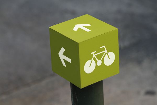 a green sign with two bicycles on it and an arrow pointing to the opposite direction