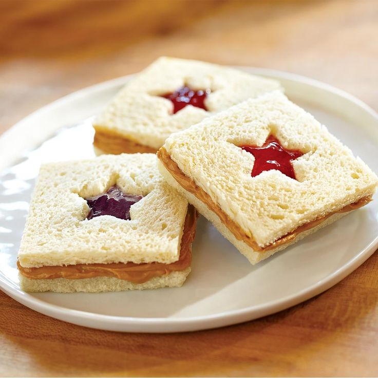 three small sandwiches with jam on them sitting on a plate