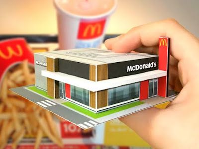 a person holding up a mcdonald's house model