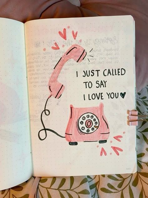 an open notebook with a drawing of a pink phone on it and the words i just called to say i love you