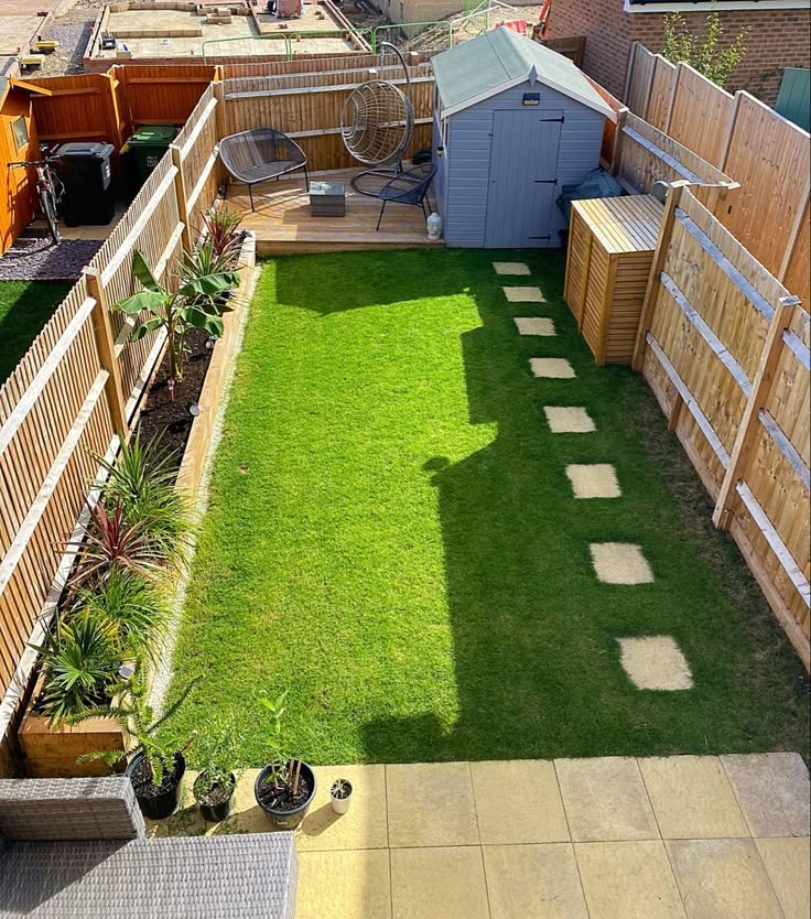 a small backyard with grass and wooden fenced in areas that are separated by fences