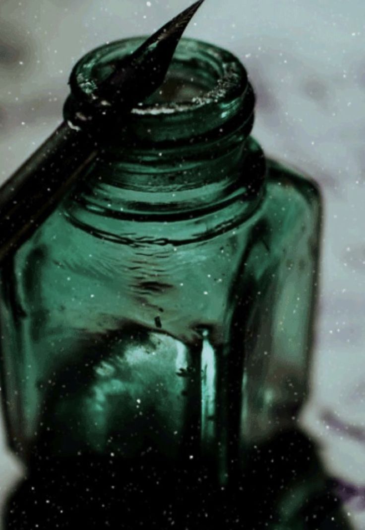 a green glass jar with a black ink pen sticking out of it