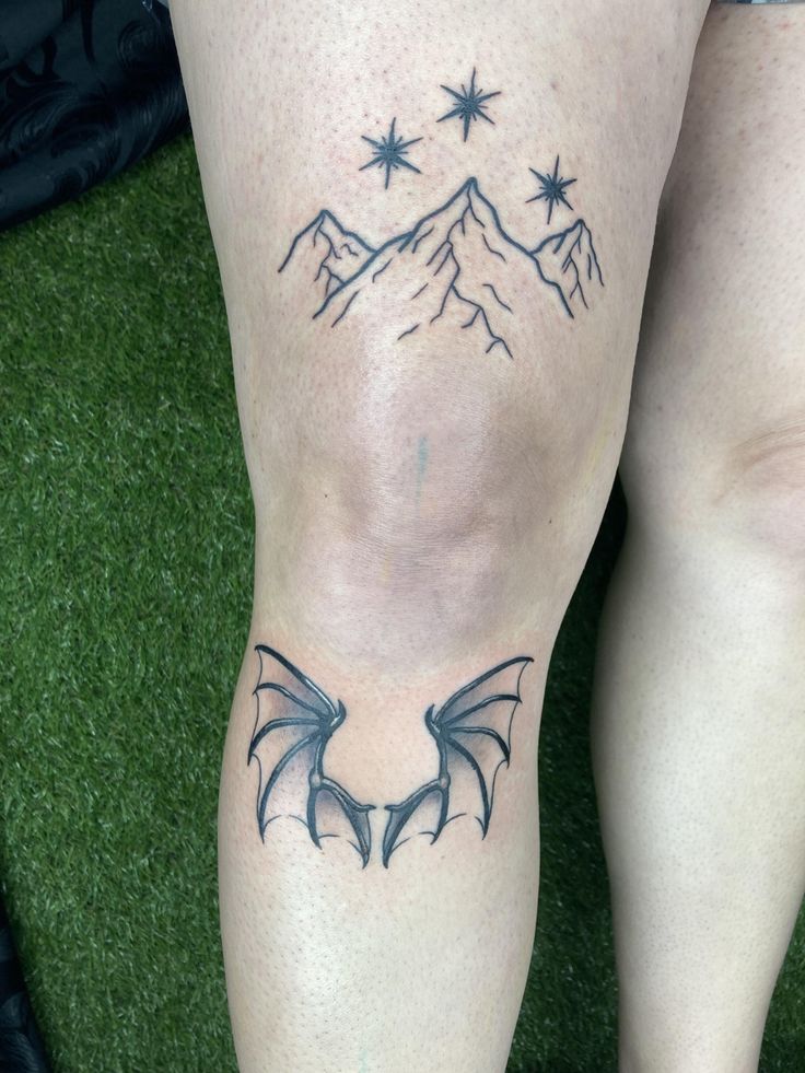 a woman's legs with tattoos on them and mountains in the back ground behind her