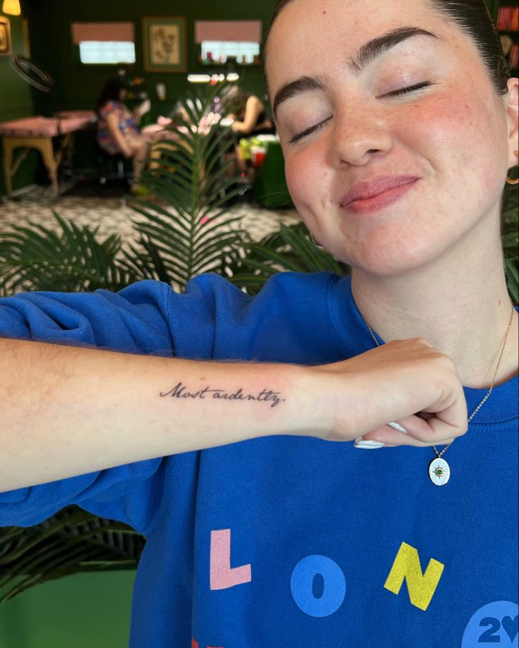 a woman wearing a blue shirt with her arm tattoo saying, not beauty on it