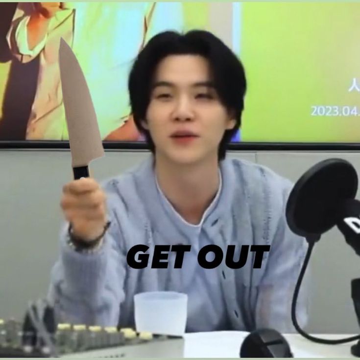 a man holding up a knife in front of a microphone with the words get out written on it